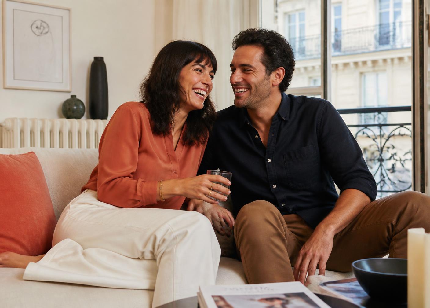 Un couple complice riant dans un salon lumineux